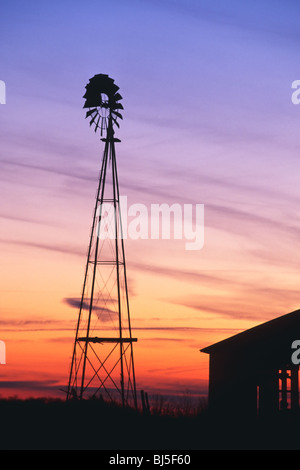 Ein schöner Sonnenuntergang mit einer Windmühle und Scheune Silhouette gegen den Abendhimmel im ländlichen Indiana USA Stockfoto