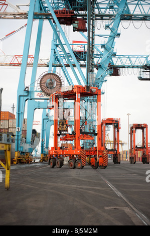 Orange Straddle Carrier Kran zum Heben von Schiffe Containern im Hafen Stockfoto