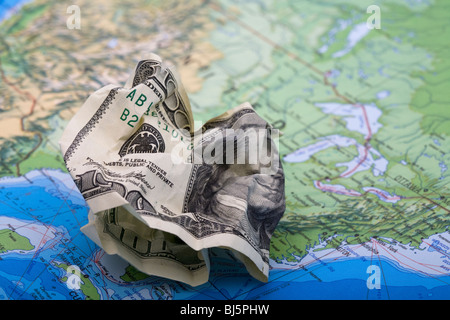 Weggeworfenes Geld. Hundert-Dollar-Rechnung auf einer Weltkarte Stockfoto