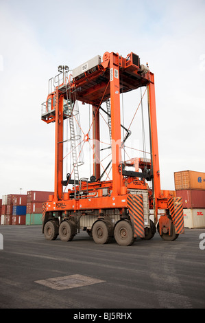 Orange Straddle Carrier Kran zum Heben von Schiffe Containern im Hafen Stockfoto