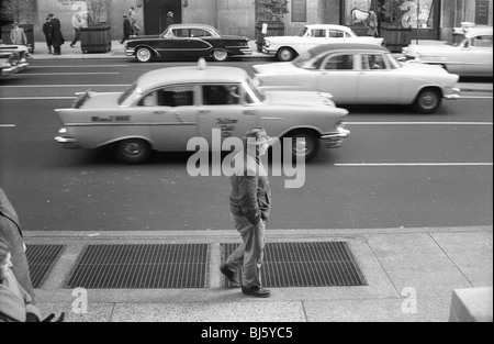 Ein 1950er Jahre Taxi geht ein Mann und anderen 50er Jahre Autos in Philadelphia. schwarze und weiße horizontale amerikanische Transport Stockfoto