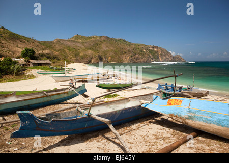 Indonesien, Lombok, South Coast, Mawun, Strand, Sonnenbaden unter bunt bemalten Fischerbooten Besucher Stockfoto