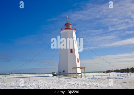 Miscou Insel-Leuchtturm, umgeben von Schnee und einem tiefblauen Himmel. Winter in Kanada Stockfoto