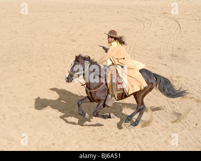 Cowboy auf einem Pferd in vollem Galopp mit Pistole in der hand Stockfoto