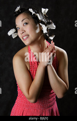 Glückliches lächelndes chinesisches Mädchen trägt einen weißen entdeckt rotes Kleid mit Papier Bindungen im Haar. Stockfoto