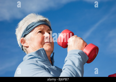 Ältere ältere Frau OAP Dame trägt ein schweißband beim Training mit hantel Trainingshanteln im Freien. Großbritannien, Großbritannien. Stockfoto