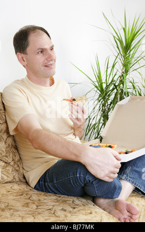Mann isst die Pizza auf dem sofa Stockfoto