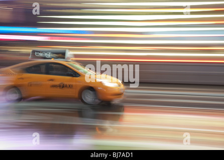 Ein gelbes Taxi ist eine Unschärfe, da es durch die Lichter des Times Square bei Nacht in New York City stürmt. Stockfoto