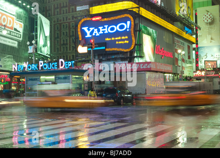 Taxis in Bewegung Rauschen der NYPD-Station auf dem Times Square vorbei an einem regnerischen Abend in New York City. Stockfoto