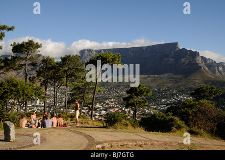 Gruppe von Jugendlichen auf Signal Hill sitzt mit Blick auf Tafelberg und die zwölf Apostel über Kapstadt Südafrika Stockfoto