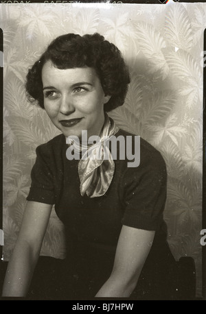 Eine modebewusste junge Frau sitzt für ein Porträt in den frühen 1950er Jahren. Schal aus Seide-Mode der 1940er Jahre schwarze Tapete Stockfoto