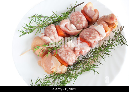 rohes Schweinefleisch Kebab auf einem Teller mit Rosmarin isoliert auf weißem Hintergrund mit Beschneidungspfad Stockfoto