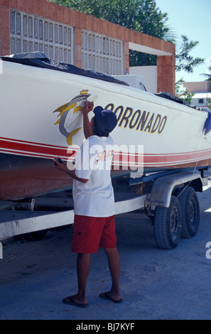 Mann, die Malerei einer Bootes in Puerto Morelos, Quintana Roo, Mexiko Stockfoto
