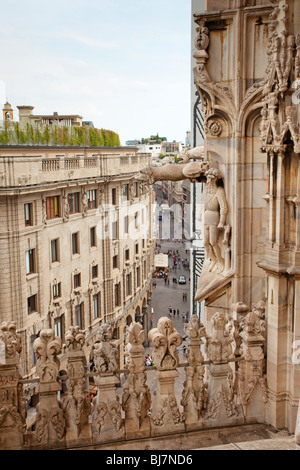 Komplizierte Steinarbeiten und Skulpturen zieren die Fassade des Mailänder Doms (Duomo di Milano) mit Blick auf die belebte Straße darunter. Stockfoto