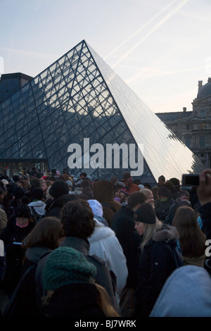 Menschen in die Warteschlange im Morgengrauen zum kostenlosen Eintritt in das Louvre Museum / Musée / Palais du Louvre, neben der Glaspyramide. Paris, Frankreich. Stockfoto