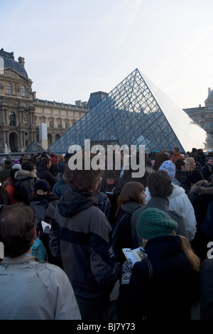 Menschen in die Warteschlange im Morgengrauen zum kostenlosen Eintritt in das Louvre Museum / Musée / Palais du Louvre, neben der Glaspyramide. Paris, Frankreich. Stockfoto