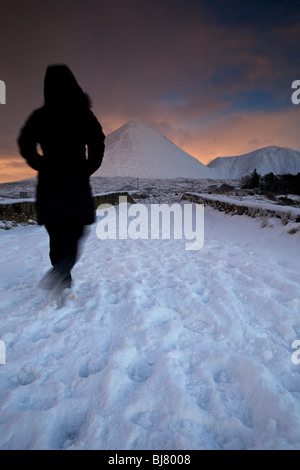 Eine Person, die zu Fuß über die Brücke Sligachan im Schnee, Isle Of Skye, Schottland Stockfoto