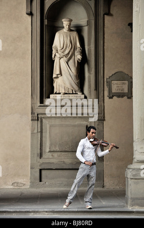 Florenz, Italien. Straßenmusiker spielt klassische Violine unter Statue der Stadt Vater Cosimo de Medici. Außerhalb der Uffizien Stockfoto