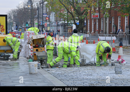 Arbeiter verlegen neue Granit Pflastersteine in High Street einkaufen Stockfoto