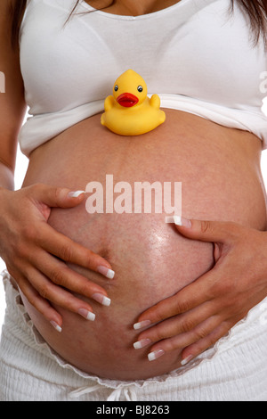 8 Monate schwangere Frau 30 Jahre alt mit kleinen gelben Childs Kunststoff Ente auf Baby-Bauch Stockfoto