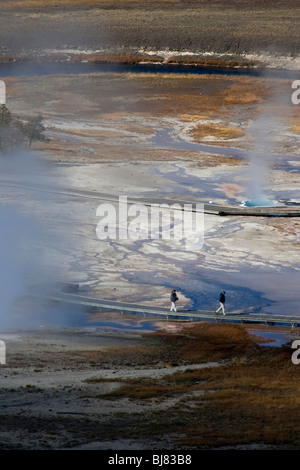 Zwei Menschen gehn entlang einem geothermischen Gebiet im Yellowstone Nationalpark, WY, USA Stockfoto