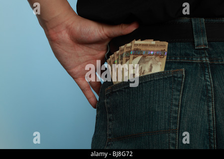 Ein Mann mit seiner Hand an seine Hüfte und ein Fan von kanadischen hundert-Dollar-Scheine ragte aus seiner Gesäßtasche. Stockfoto