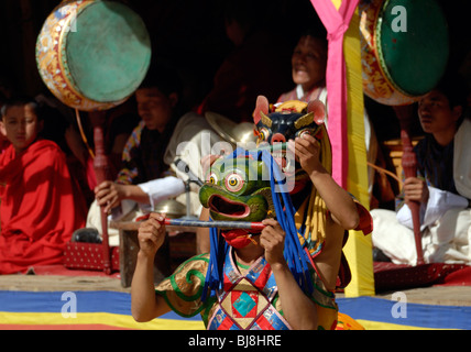Ein Mönch-Tänzer in einer Maske für eine Eule tanzt vor der Band im Rathaushof von Monga Dzong Stockfoto