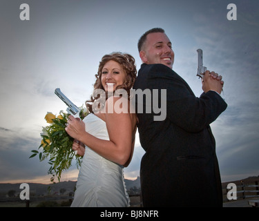 Ein paar stehen Rücken an Rücken bereit für eine spielerische Duell mit Kappe Gewehren auf ihrer Hochzeit. Stockfoto