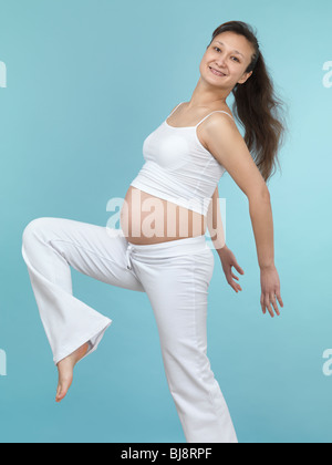 Lächelnde junge schwangere Frau in weißen sportlichen Outfit. Siebten Monat der Schwangerschaft. Stockfoto