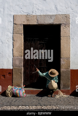 Ein Mann spinnt einen Korb, um Touristen vor einer Tür einer kolonialen Hause in Taxco de Alarcón, Bundesstaat Guerrero, Mexiko zu verkaufen. Stockfoto