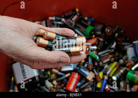 Womans Hand hält Haushalt AA-Batterien über die gelbe Tonne Stockfoto