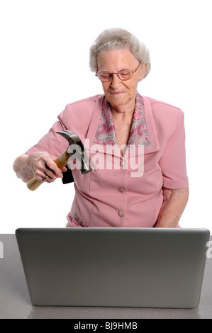 Ältere Frau brechen Laptop-Computer mit hammer Stockfoto
