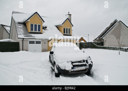 dh AVIEMORE INVERNESSSHIRE Schneebedecktes Auto im Gartenhaus Fahrt verschneiten Winter schottland Zuhause Exterior scottish Highlands Winterzeit eiskalt großbritannien Stockfoto