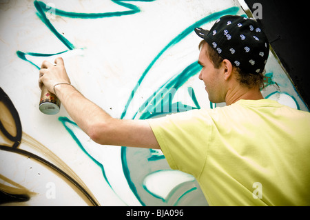 Junge kaukasische männliche Graffiti-Künstler mit Dose Aerosolfarbe in der Hand schaffen Street Art Stockfoto