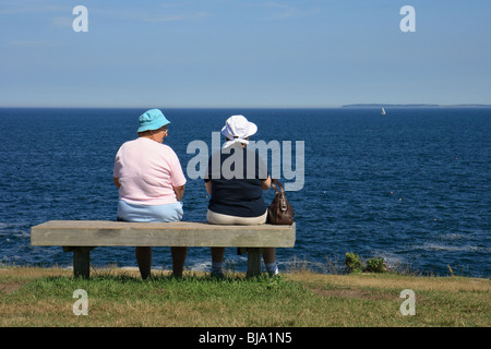 Zwei Frauen sitzen auf einer konkreten Bank ein Panorama des Atlantischen Ozeans, Bar Harbor, USA Stockfoto