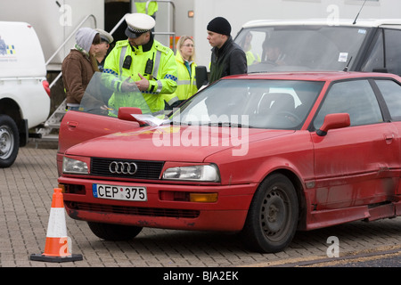 Ein Polizist überprüfen und im Gespräch mit ausländischen Autofahrer bei gemeinsamen VOSA und Polizei-checkpoint Stockfoto