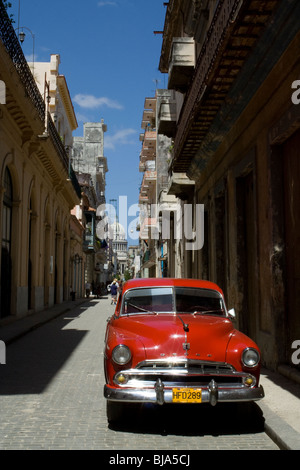 Klassisches rotes Auto - klassisches amerikanisches Ausweichen im Alten Havanna und das Kapitol der Stadt in der Ferne, Altes kubanischer Auto in Havanna Kuba, Reise in die Karibik Stockfoto