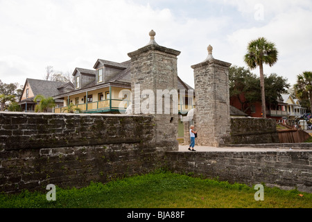 Ein junges Mädchen an das alte Stadttor Säulen gebaut von Coquina sind eine bekannte Sehenswürdigkeit in St. Augustine, Florida Stockfoto