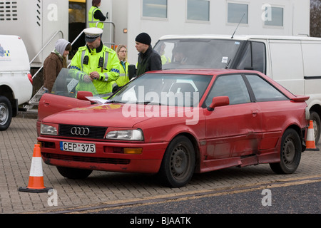 Ein Polizist überprüfen und im Gespräch mit ausländischen Autofahrer bei gemeinsamen VOSA und Polizei-checkpoint Stockfoto