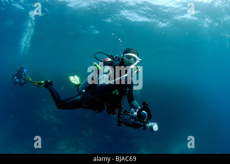 Scuba Diver tun th Zeichen "OK" mit einer Hand und halten Sie eine Kamera. Stockfoto