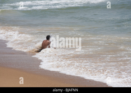 Ein Mann sitzt in der Brandung am Strand von Puri, Orissa, Indien Stockfoto