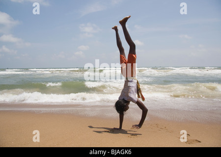 Ein junger Mann geht auf seine Hände am Strand von Puri in Orissa, Indien Stockfoto