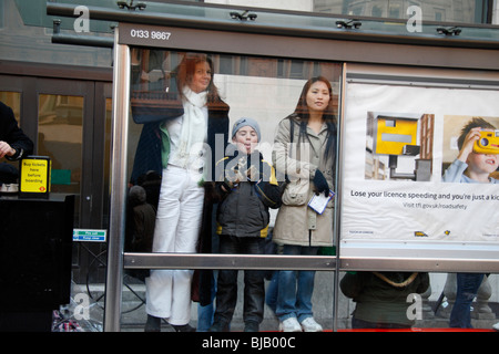 Kind zieht Gesicht und seine Zunge bei einem Fotografen an einer Bushaltestelle in London, Vereinigtes Königreich. Stockfoto