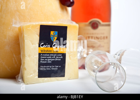 Ein Feier-Turm der ganzen Runde Käse mit einem großen Keil von Blauschimmelkäse mit einer Flasche Champagner und zwei Gläser Stockfoto