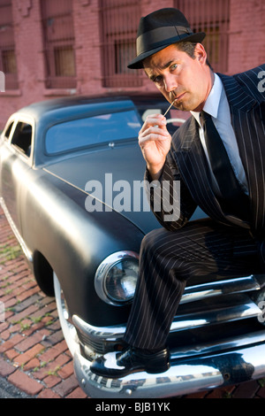 Mann im Anzug mit Zahnstocher stützte sich auf Kotflügel Oldtimer Stockfoto