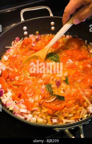 Man bereitet eine Tomatensauce auf einer Pfanne in Küche. Stockfoto