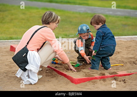 Mutter mit Kindern im Sandkasten spielen Stockfoto
