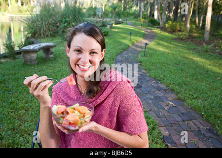 Schwangere Frau im Park Essen Obstsalat Stockfoto