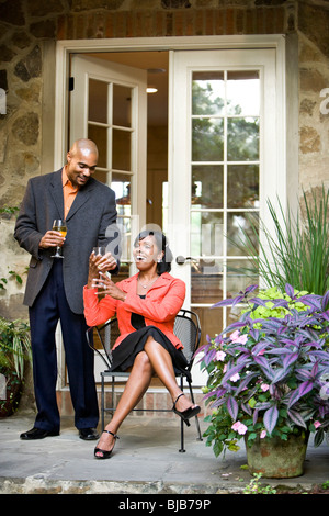 Mittleren Erwachsenenalter Afro-Amerikaner auf Gartenterrasse paar, Mann, bringen Wein Stockfoto