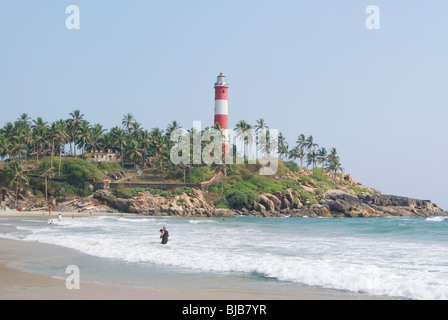 Kovalam Beach.Tourist genießen Bad im schönen ruhigen Arabisches Meer. Ausweitung der felsigen Kokospalmen und Kovalam Leuchtturm Landschaft Stockfoto